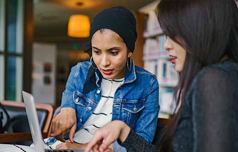 two women discussing in front of computer